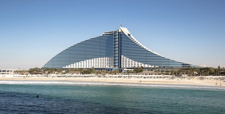 نمای نمادین هتل Jumeirah Beach Hotel با طراحی موجی و ساحل اختصاصی کنار خلیج فارس – از قدیمی‌ترین هتل های ساحلی دبی