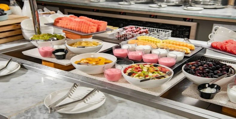 میز صبحانه کامل هتلی با نان، غلات و آب‌میوه — تفاوت فولبرد و هافبرد در هتل